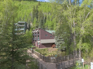 Un chalet doté d’une terrasse en bois, entouré d’une forêt dense.