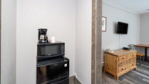 Una kitchenette con microondas, cafetera y un armario de madera.