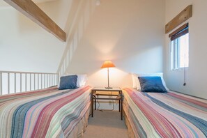 A bedroom with two beds, a small table, and a lamp.