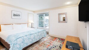 Ein Hotelzimmer mit Bett, Fernseher, Fenster und Holztisch.