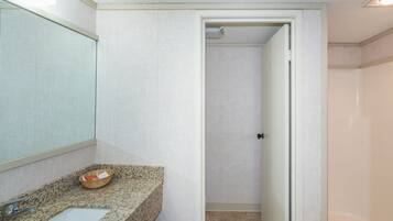 Een badkamer met een granieten aanrechtblad, een spiegel, een wastafel en een douchehoek.