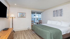 Une chambre à coucher avec un lit, un bureau, une lampe, une fenêtre et des œuvres d’art accrochées aux murs.