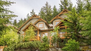 A row of log cabin-style buildings with wooden balconies and surrounded by dense forest.