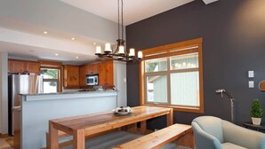 A modern kitchen with wooden cabinets, a central island, and a dining area with a bench and chair.
