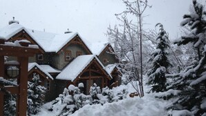 A lodge with a wooden exterior, snow-covered roofs, and surrounding snow-laden trees.