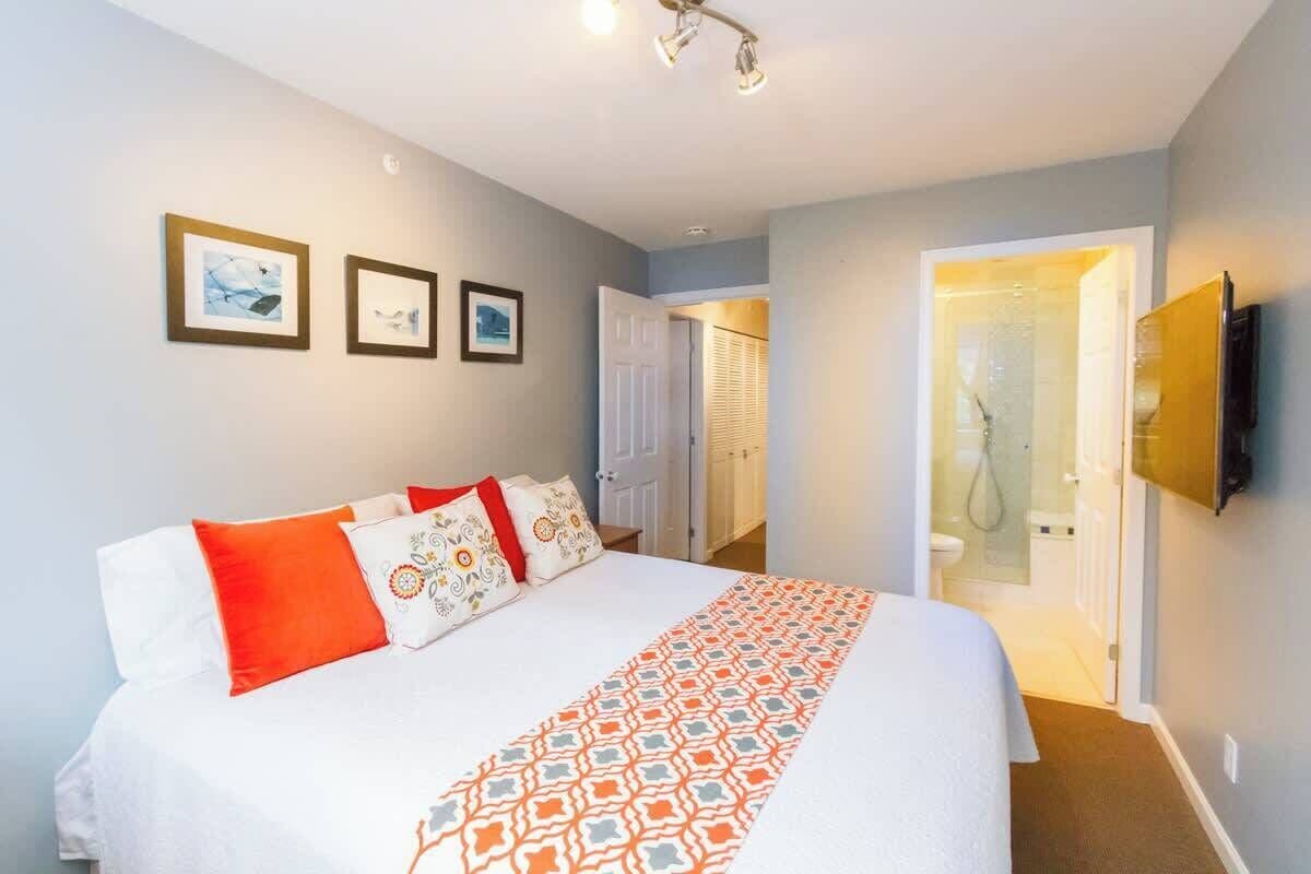 A bedroom with a bed, a shower, and a TV.