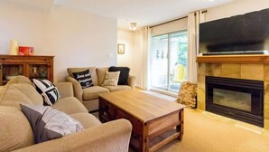 A living room with a sofa, a coffee table, a fireplace, and a television. - Gorgeous 2 Bed, Village location, Shared Hot Tub (Whistler)