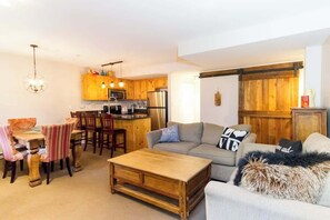Uma sala de estar aconchegante com um sofá, mesa de centro e espaço para refeições.