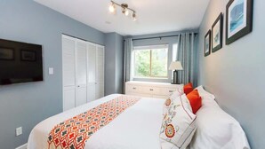 A bedroom with a bed, a window, a dresser, and a TV mounted on the wall. - Gorgeous 2 Bed, Village location, Shared Hot Tub (Whistler)