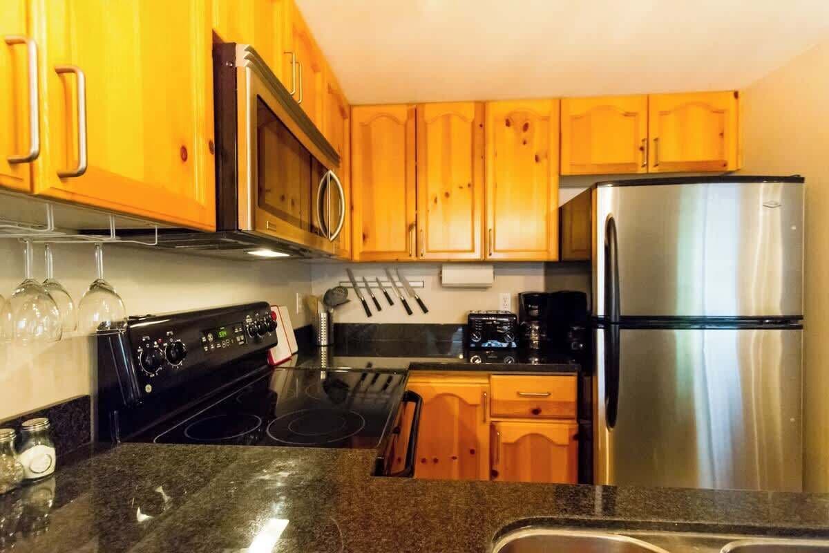 A kitchen with wooden cabinets, stainless steel appliances, and a granite countertop.