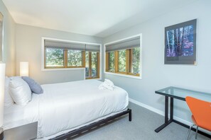 A hotel room with a bed, a desk, and a chair. There are windows with blinds, a painting on the wall, and a carpeted floor. - Newly Remodeled Condo Across from Lift 7 | Walk Downtown-Pool/Hot Tub (Telluride)