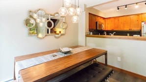 A dining area with a wooden table, a bench, and a mirror with circular frames on the wall. - Ski Home, Free Shuttle, Communal Hot Tub (Whistler)