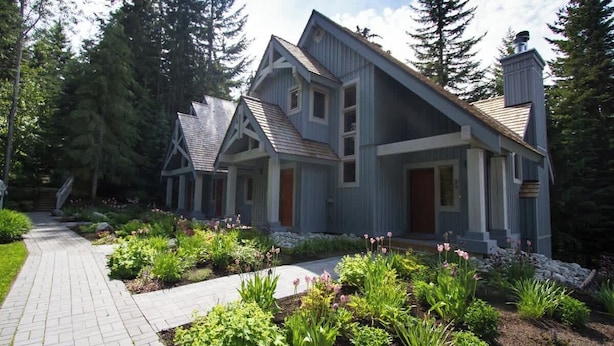 A modern house with a sloped roof, a front porch, and a landscaped garden with various plants and a pathway. - Ski Home, Free Shuttle, Communal Hot Tub (Whistler)