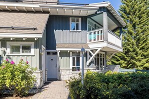 A two-story house with a balcony, a front door, and a pathway leading to the entrance.