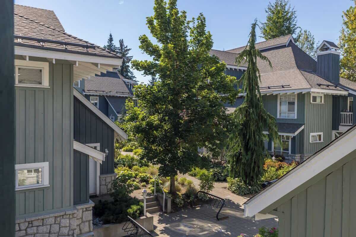Un quartier résidentiel avec des maisons, un arbre et un chemin pavé de pierres.