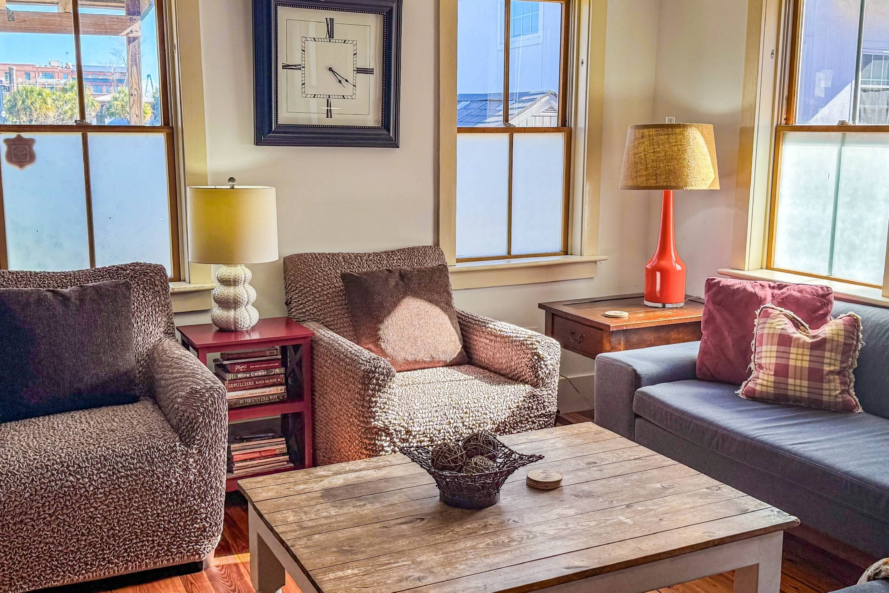 A cozy living room with patterned furniture, a wooden coffee table, and a clock on the wall.