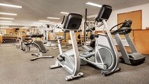 Un gimnasio con diversos equipos de ejercicio, incluyendo cintas de correr, elípticas y máquinas de pesas.