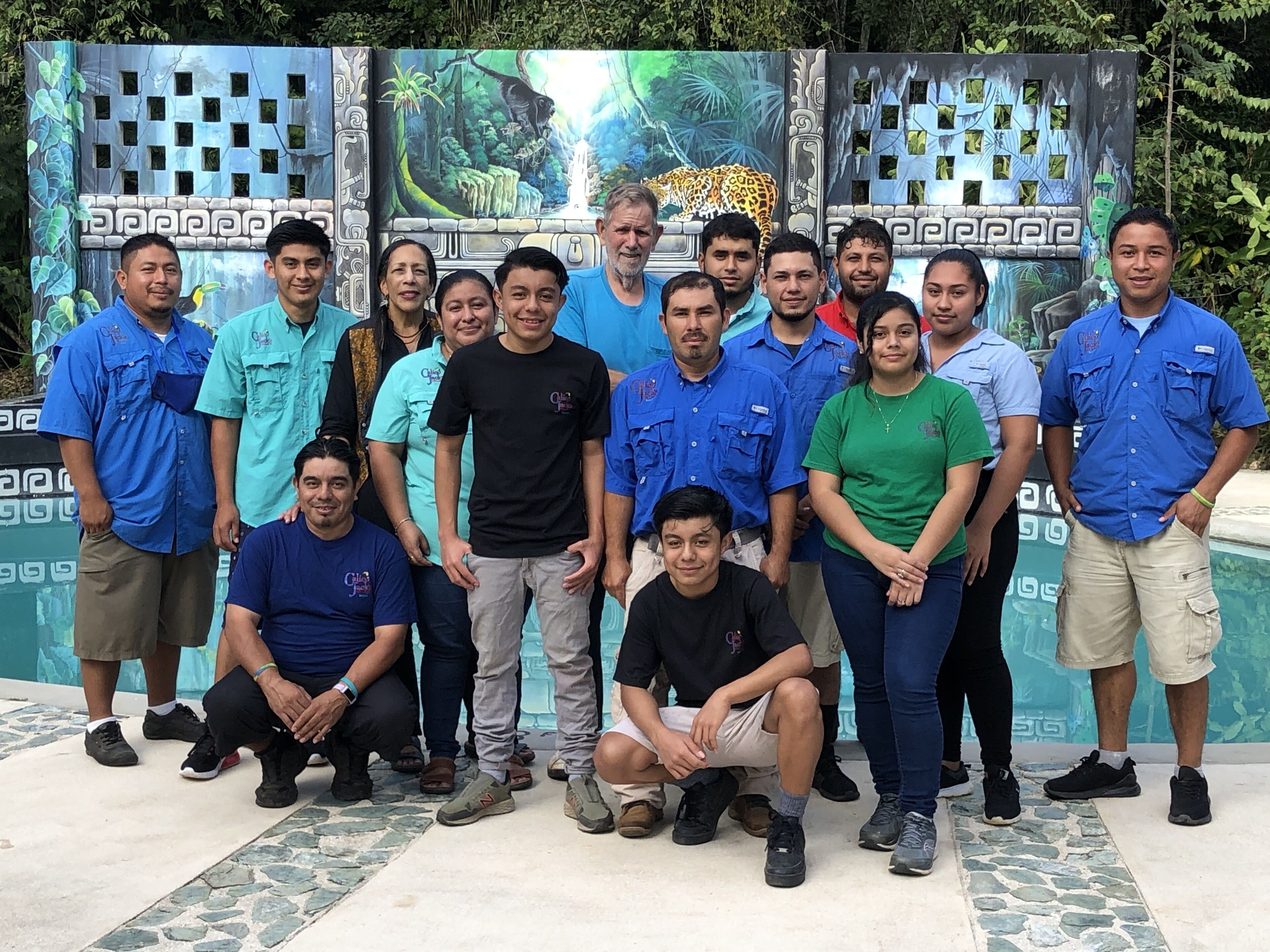 A group of people posing in front of a decorative backdrop with a jungle theme.