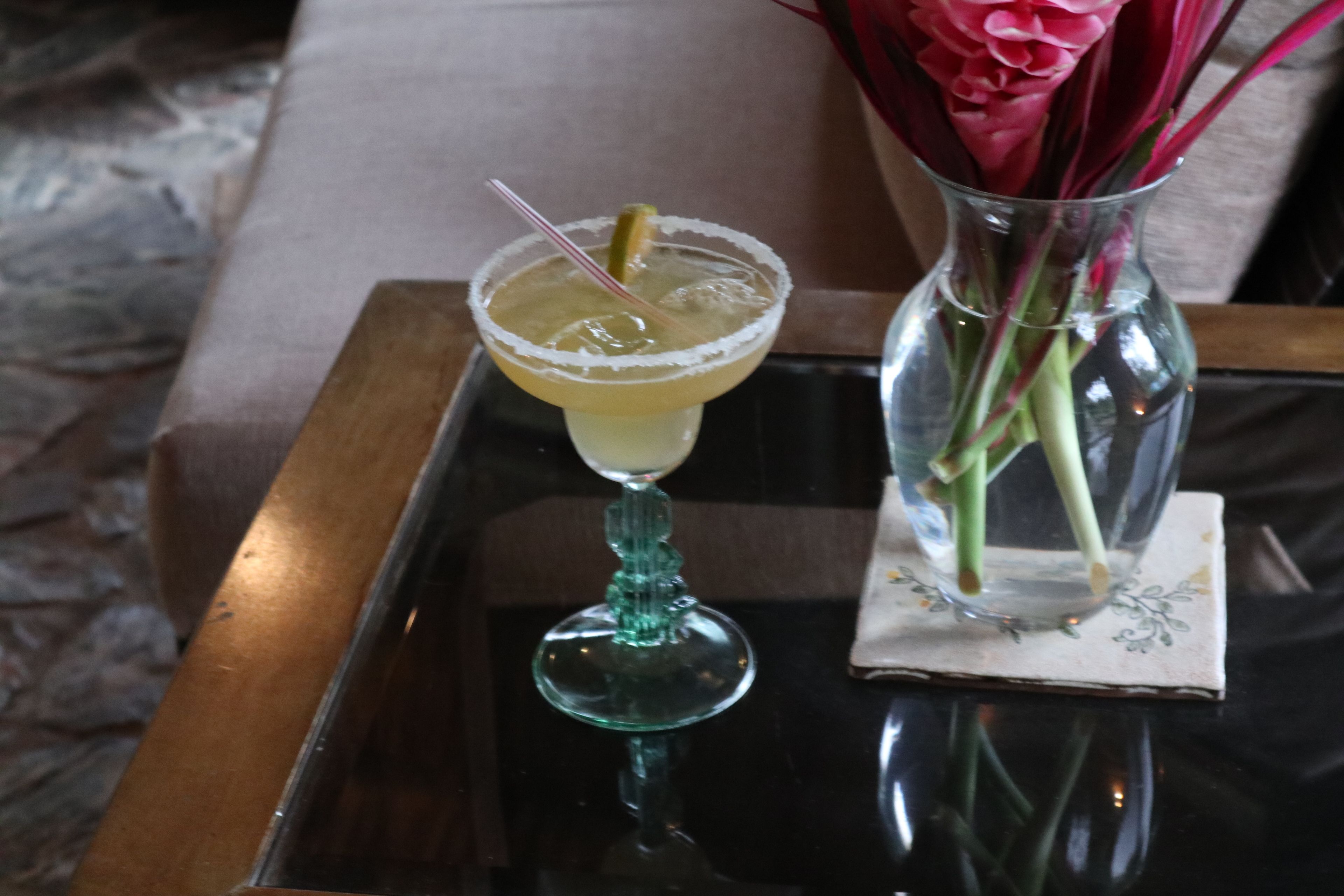 Un cocktail servi dans un verre dont le bord est saupoudré de sel, posé sur un plateau réfléchissant.