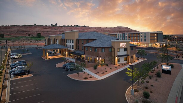 A hotel with a parking lot, multiple buildings, and a desert landscape in the background.