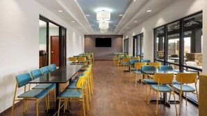 A conference room with tables and chairs, a flat-screen TV, and large windows.