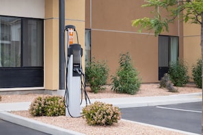An electric vehicle charging station, a building with large windows, and a landscaped area with small bushes. - Garner by IHG Page at Lake Powell (Page)