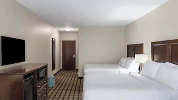 Une chambre d’hôtel avec deux lits, une télévision, une commode et une porte donnant sur une autre pièce.