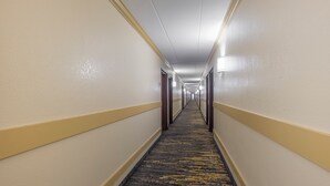 A hotel hallway with carpeted floors, doors on both sides, and overhead lighting. - Red Roof Inn Annapolis (Annapolis)