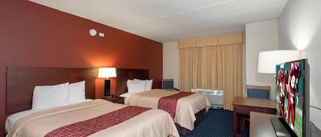 A hotel room with two beds, a desk, a television, and a window with curtains.