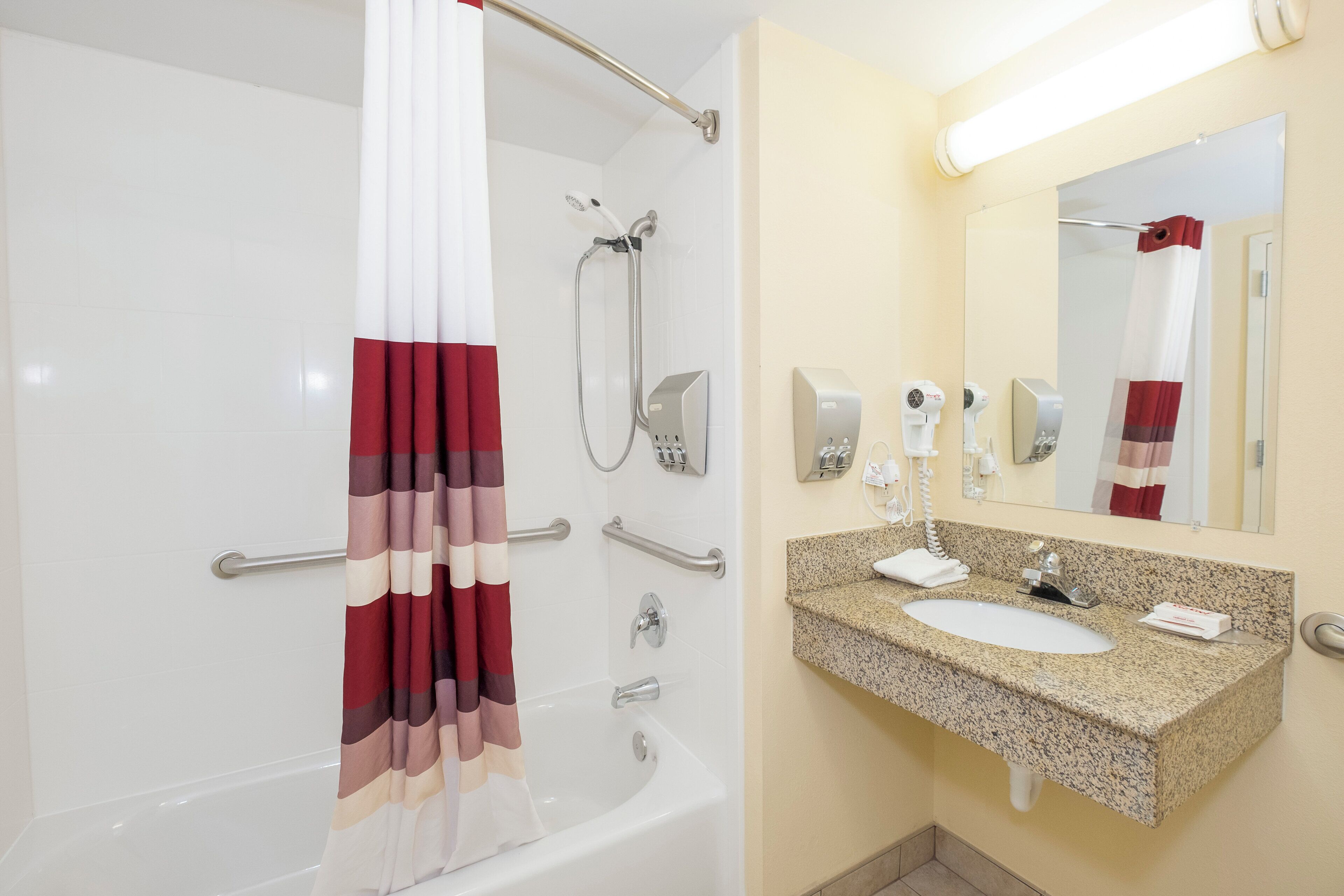 Une salle de bain équipée d’une baignoire, d’une douche et d’un lavabo en granit avec un miroir au-dessus.