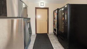 A hallway with a stainless steel refrigerator, a vending machine, and a door. - Red Roof Inn Annapolis (Annapolis)