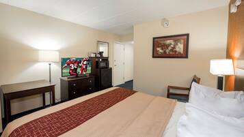 A hotel room with a bed, a desk, a television, a coffee maker, and a framed picture on the wall.