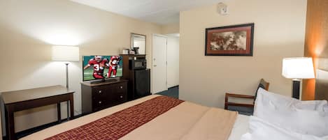 A hotel room with a bed, a desk, a television, a coffee maker, and a framed picture on the wall.