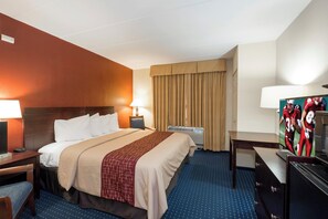 A hotel room with a bed, bedside tables, a desk, a TV, and a window with curtains. - Red Roof Inn Annapolis (Annapolis)