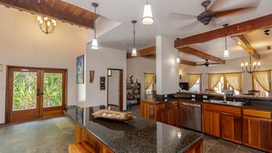 Una cocina amplia con encimera de granito, armarios de madera y una isla central con taburetes.