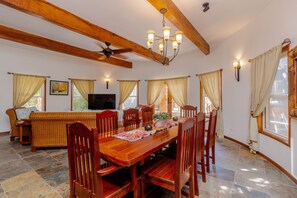 Un comedor amplio con mesa y sillas de madera, un sofá y un ventilador de techo.
