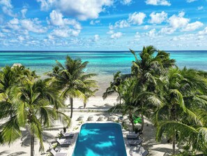 Vista della piscina con una spiaggia e palme ben visibili.