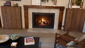 A living room with a fireplace, wooden furniture, a television, and a framed picture on the wall. - Secluded Cozy Cottage: Walk to Town, Private (Idyllwild)