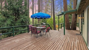 A wooden deck with a table and chairs, surrounded by tall trees. - Secluded Cozy Cottage: Walk to Town, Private (Idyllwild)