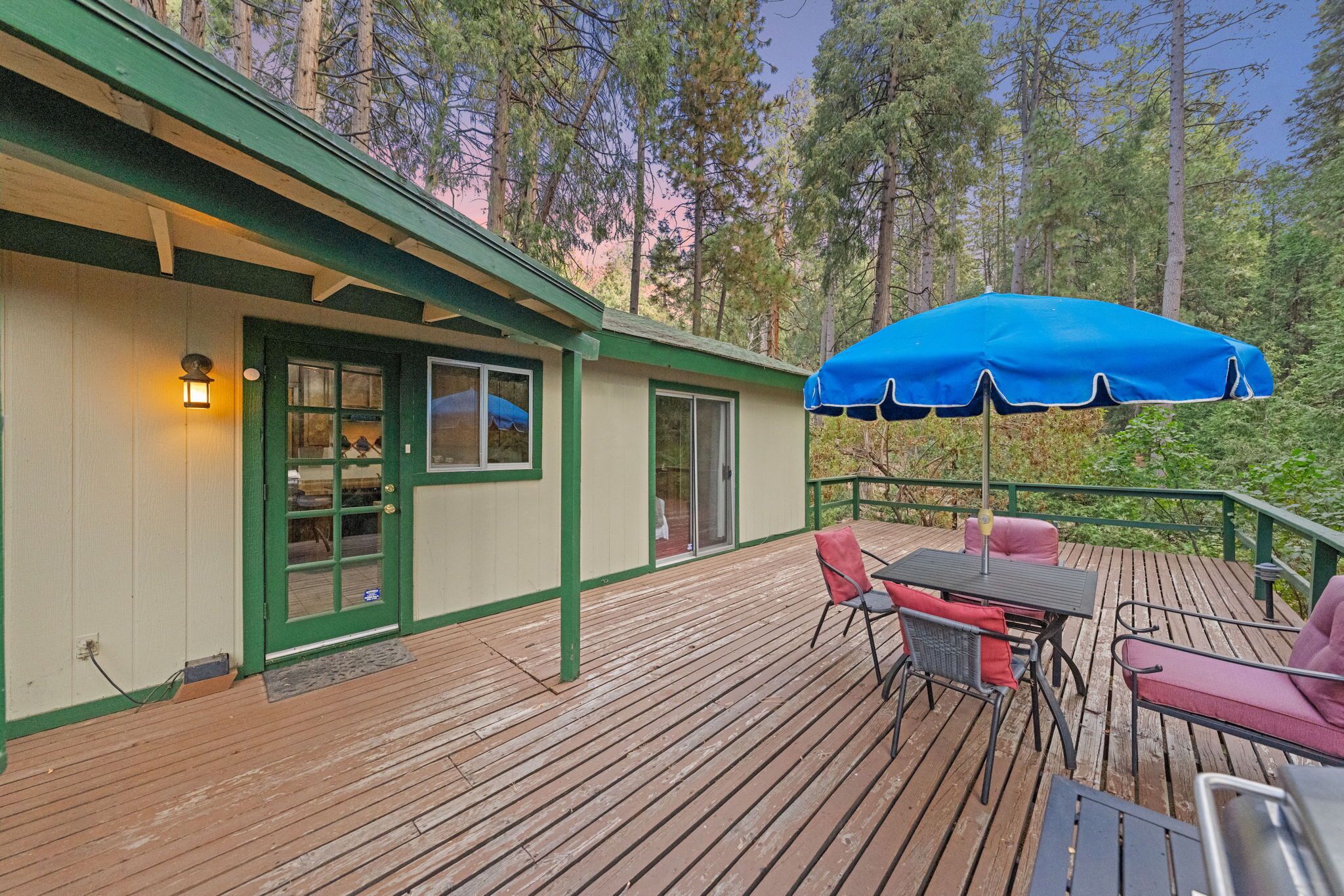 Una terraza de madera con mobiliario exterior y un paraguas azul.