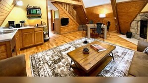 A cozy loft-style living space with a kitchen, dining area, and a fireplace. - A-Frame #18 - Hosted by The Chalets (Logan)