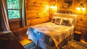 Un dormitorio de cabaña de madera acogedor, con una cama grande, una ventana con cortinas y un tapiz decorativo.