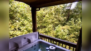 Un jacuzzi con terraza de madera y vista a zona boscosa.