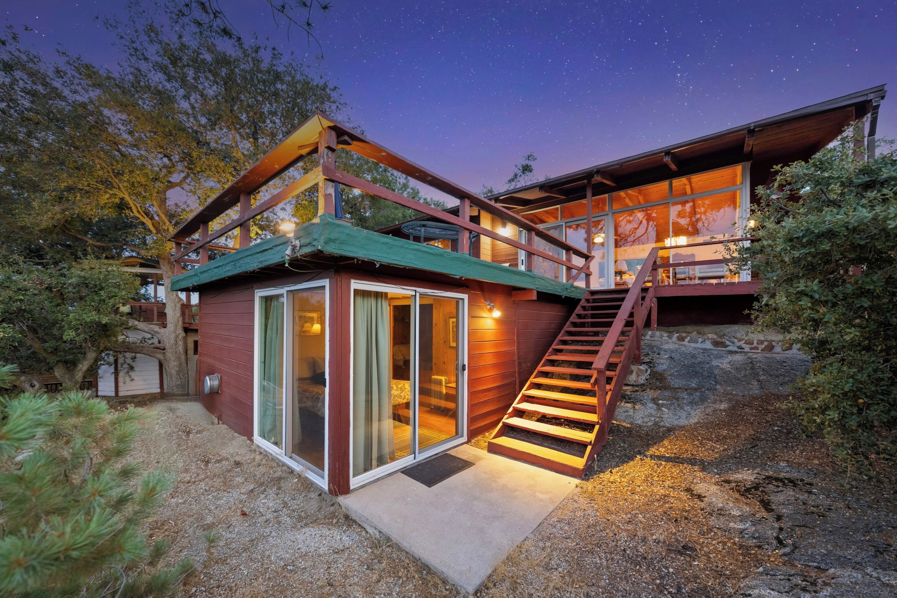 Ein modernes Haus mit Glastür, Holzterrasse und einer Treppe zu einer oberen Etage.