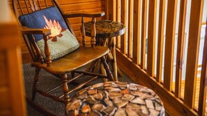 A wooden rocking chair with a quilted cushion and a small round ottoman with a woven design. - Fireside Lodge - Hosted by The Chalets (Logan)