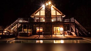 A two-story building with a glass facade, a pool in the foreground, and a staircase leading to the upper level. - Fireside Lodge - Hosted by The Chalets (Logan)