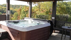 A hot tub in a covered outdoor area with a view of trees and hills. - Big Sky Lodge - Hosted by The Chalets (Logan)