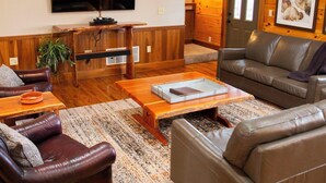 A cozy living room with a flat-screen TV, leather sofas, a wooden coffee table, and a large rug. - Big Sky Lodge - Hosted by The Chalets (Logan)