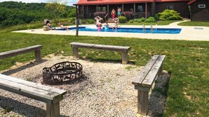 A log cabin with a swimming pool, surrounded by a well-maintained lawn and a fire pit. - Big Sky Lodge - Hosted by The Chalets (Logan)