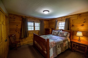 Cozy bedroom with a large bed, wooden nightstand, and a comfortable chair.